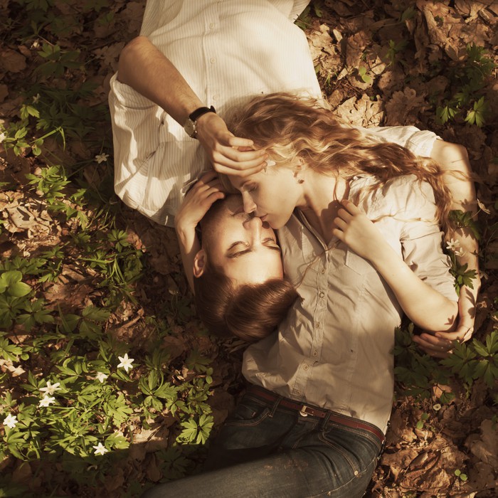 Wall Mural beautiful couple lying in a meadow in spring - PIXERS.UK