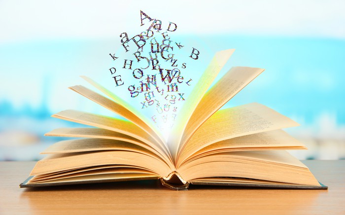 Fotobehang Open boek met letters op een lichte achtergrond